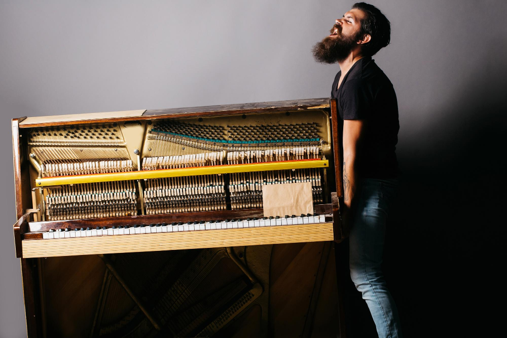 homme barbu essayant deplacer piano bois